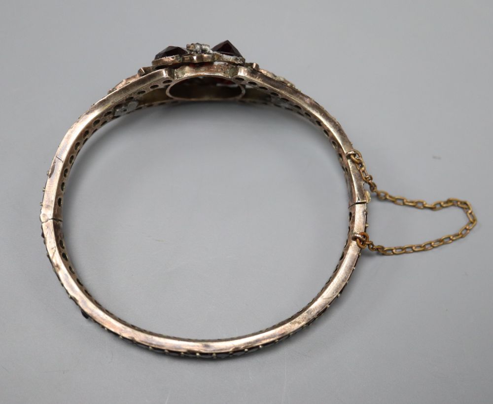 A Victorian gilt white metal and garnet set hinged bangle.